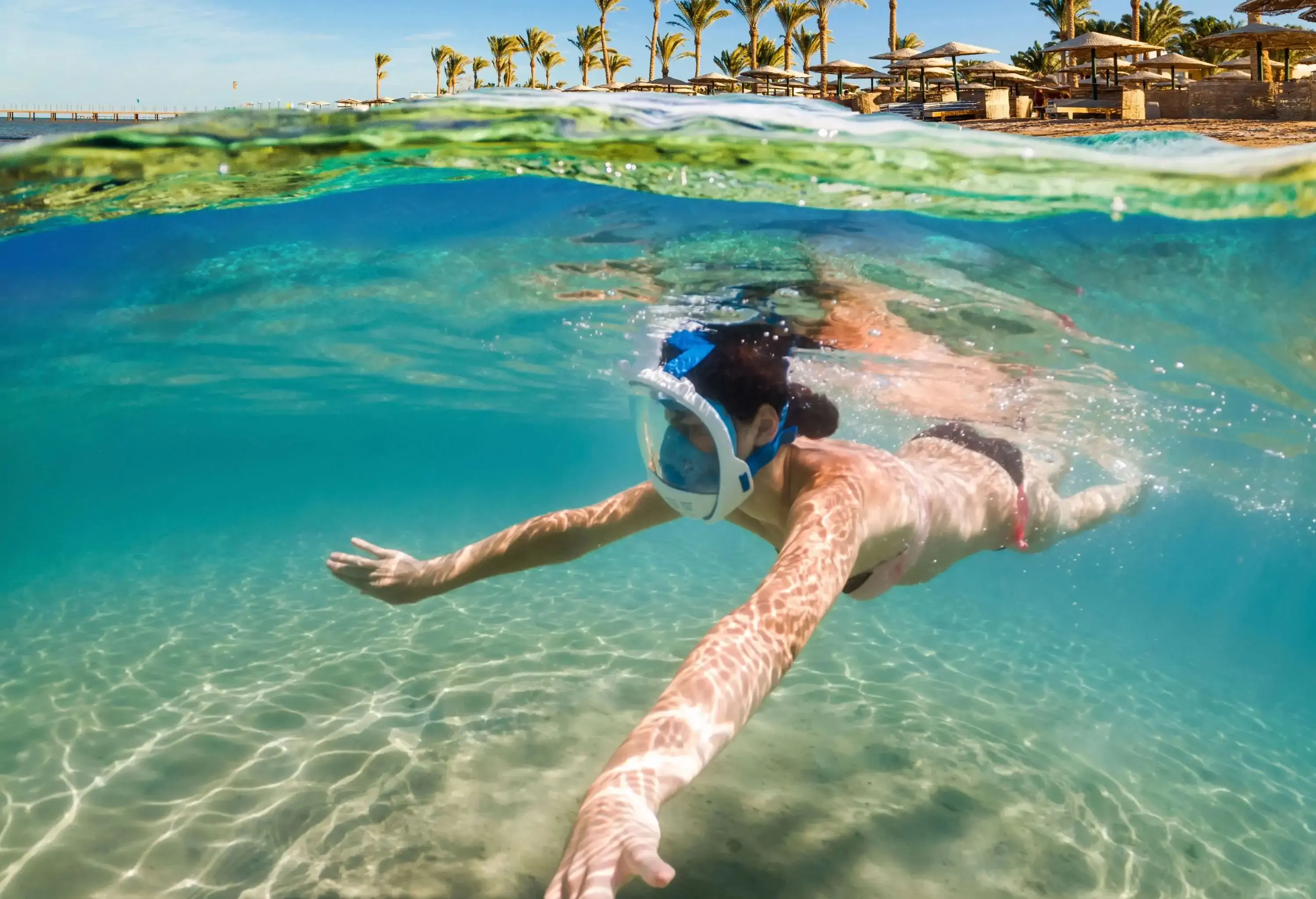 A woman in a bathing suit dives underwater with a snorkelling mask.