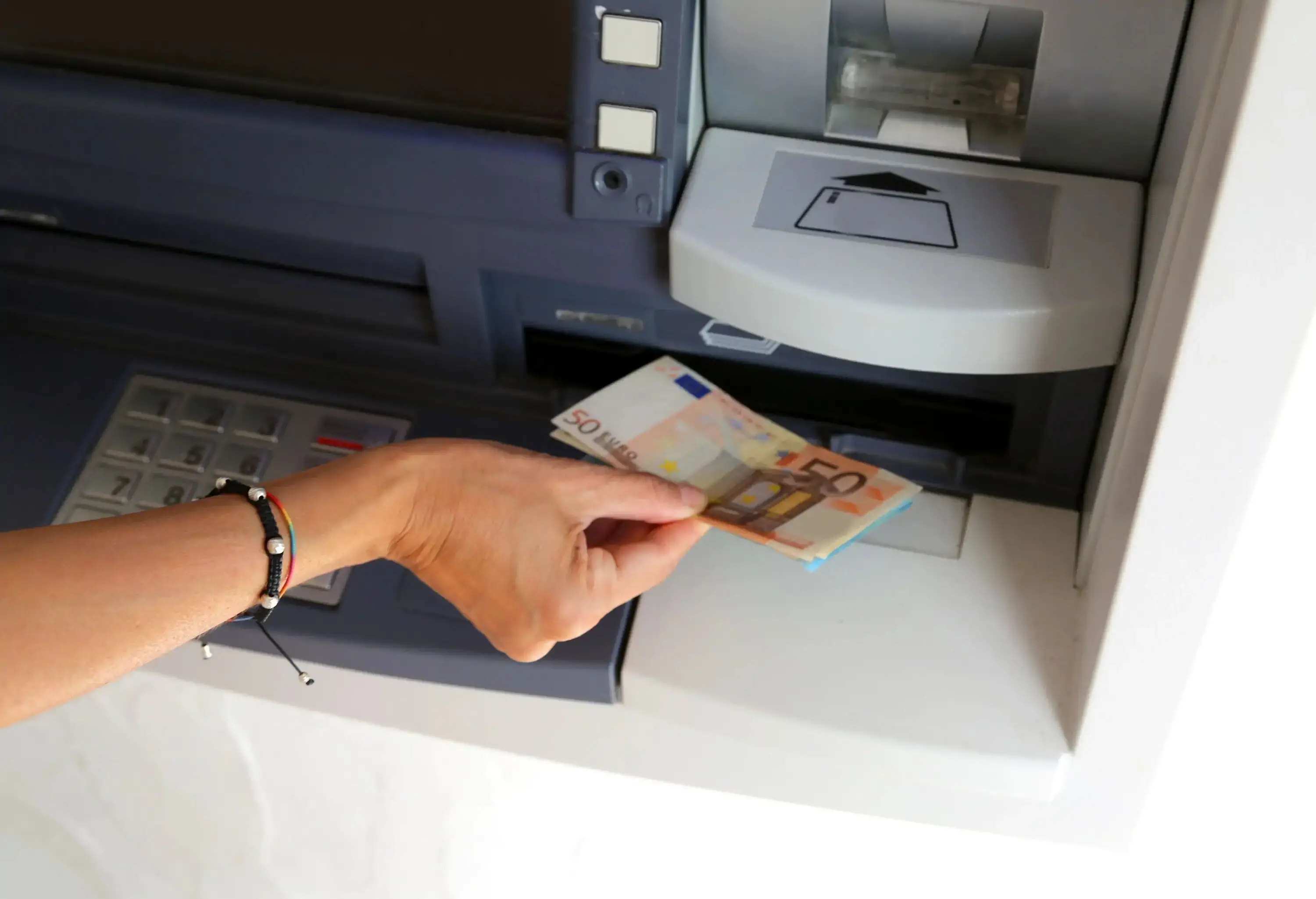 A hand withdraws money from an ATM.