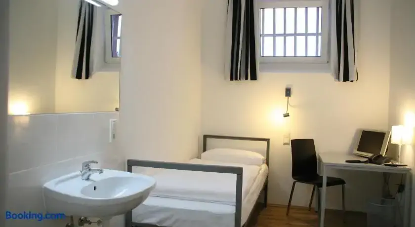Zimmer-Zelle im Alcatraz Hotel mit spartanischem Bett und Waschbecken