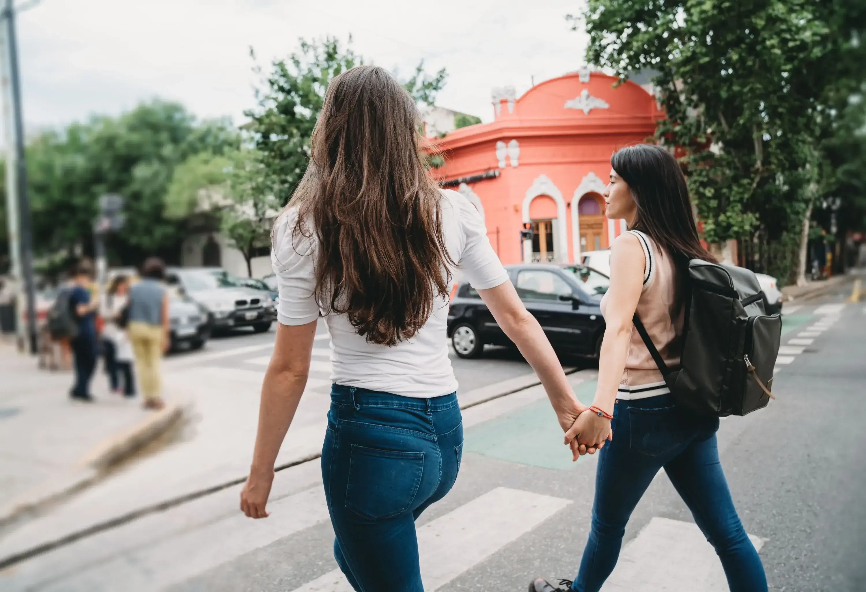 Two people holding hands as they cross a pedestrian lane.