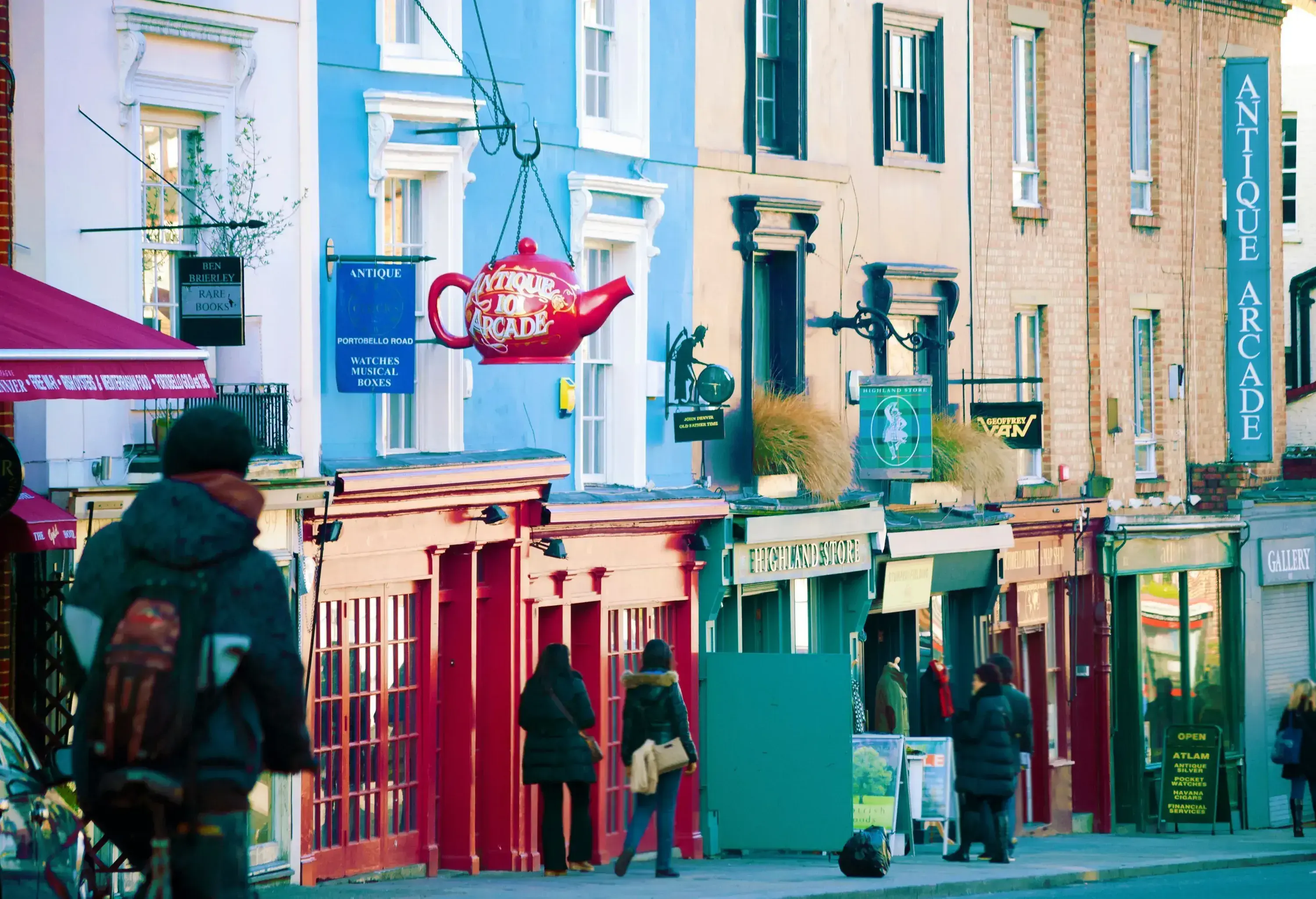People stroll on a street along the terraced buildings of shops, cafés, and commercial establishments.