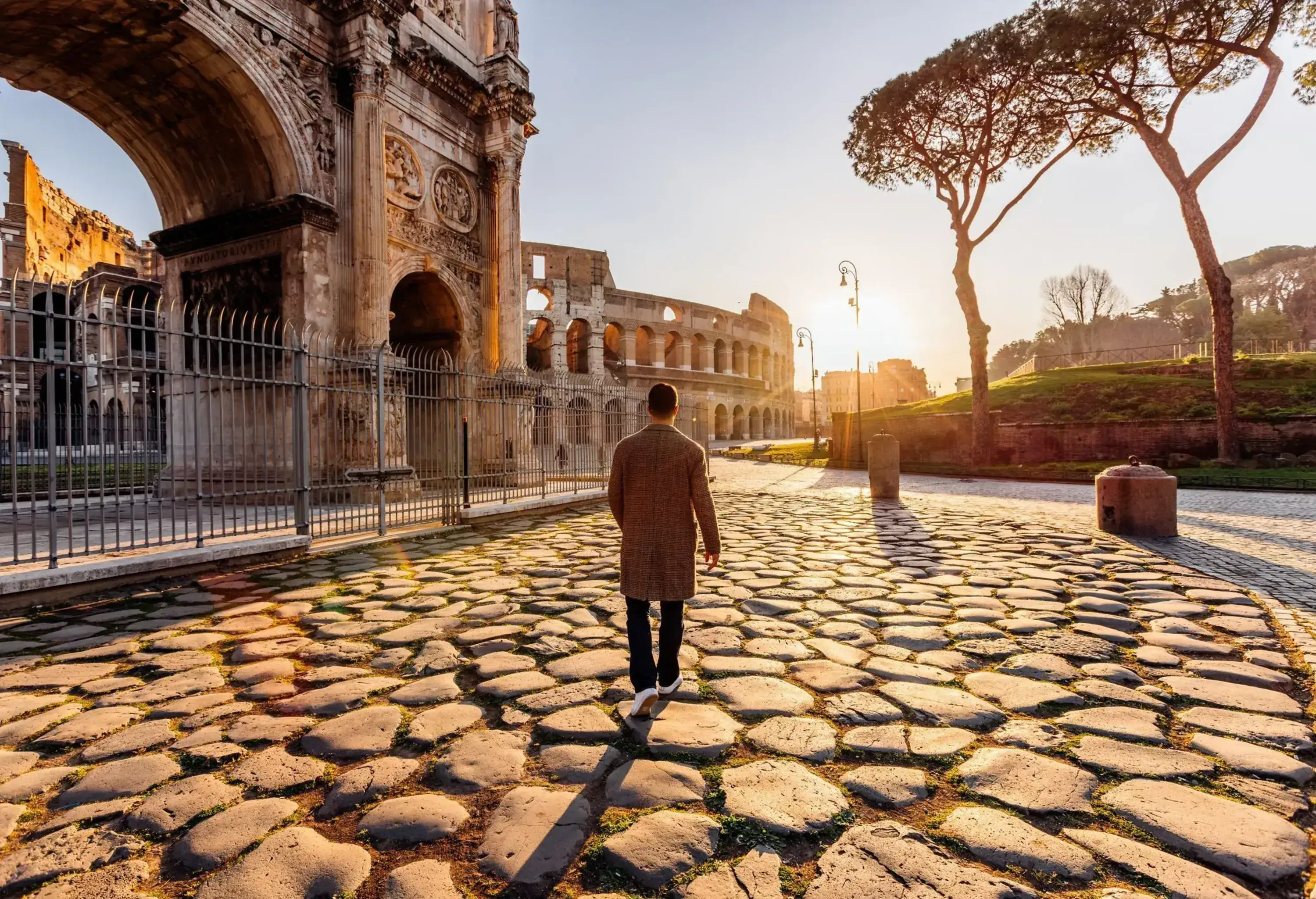 A man walks towards the Coliseum in Rome at sunrise