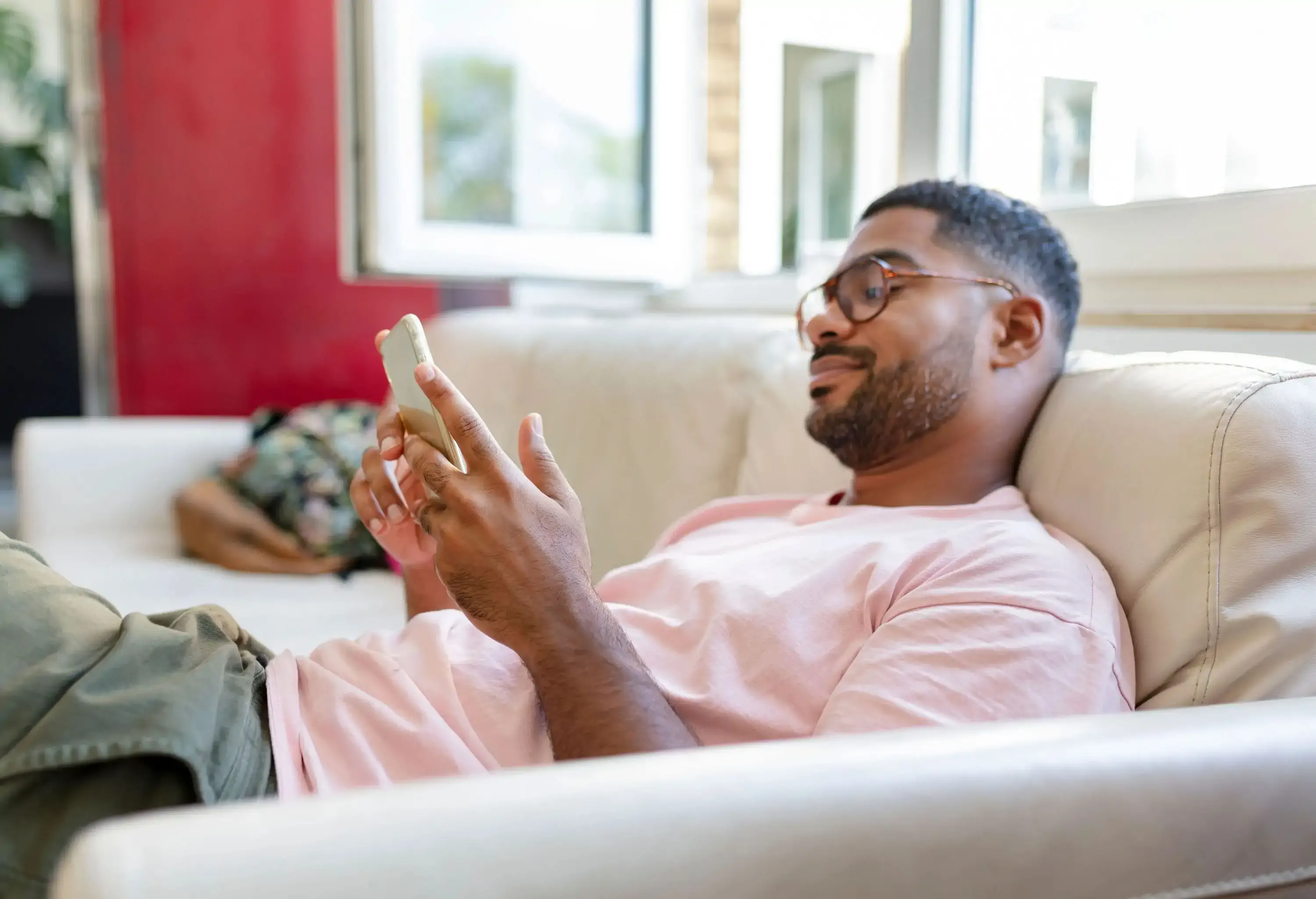 A man sitting comfortably on the couch while using his smartphone.