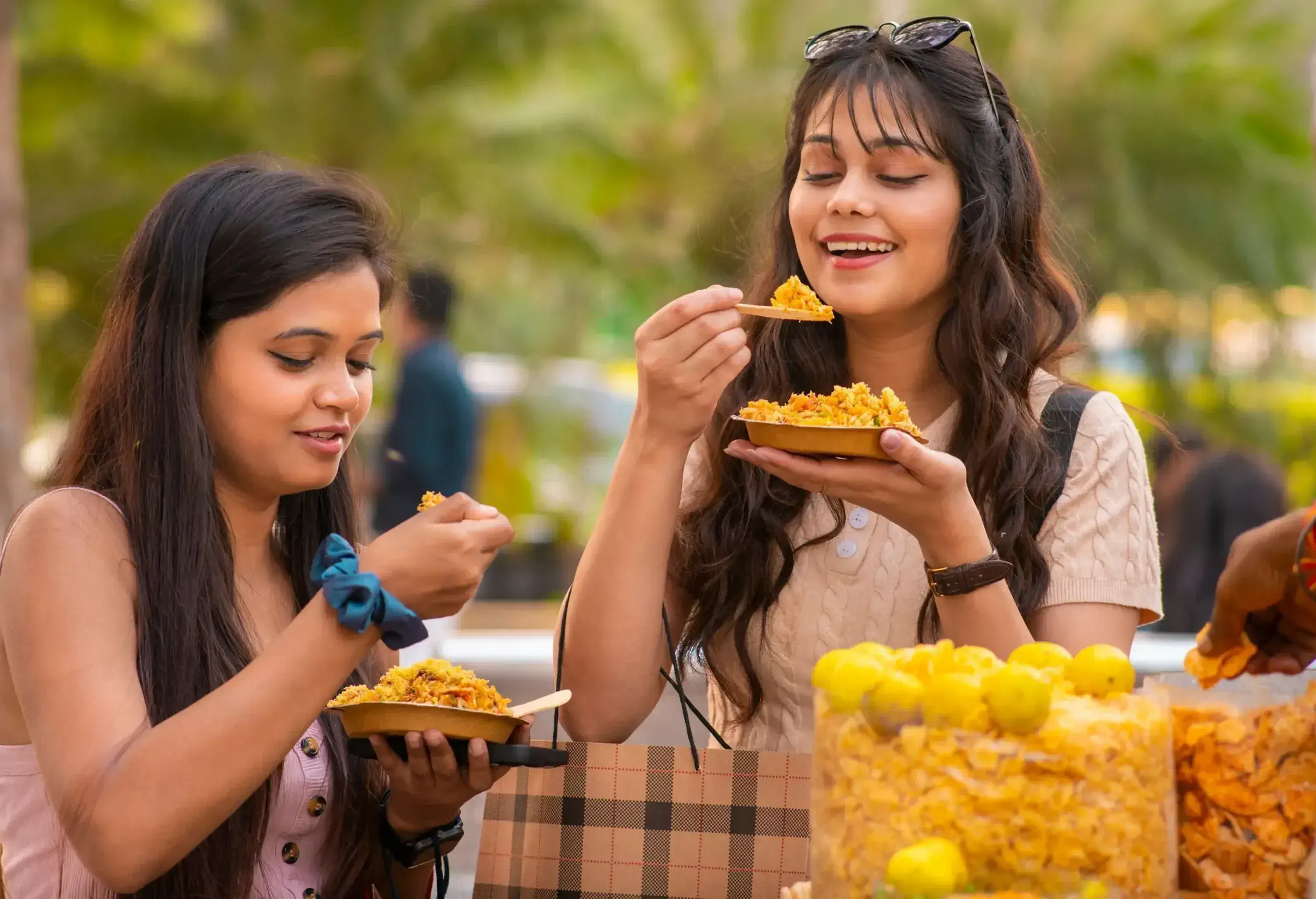Two happy indian women eating popular indian street snack (Bhelpuri) at street market