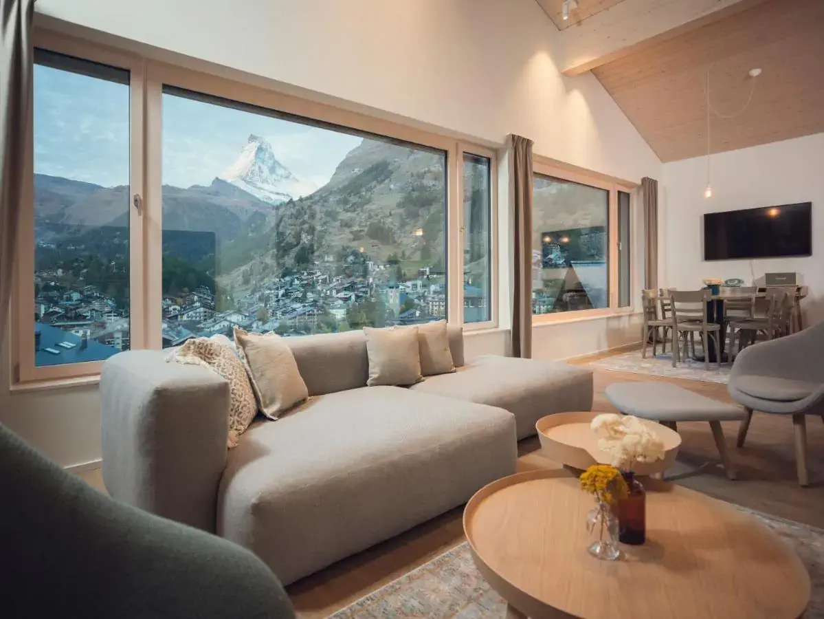Suite in a mountain hotel decorated in neutral tones overlooking a snow-capped mountain peak