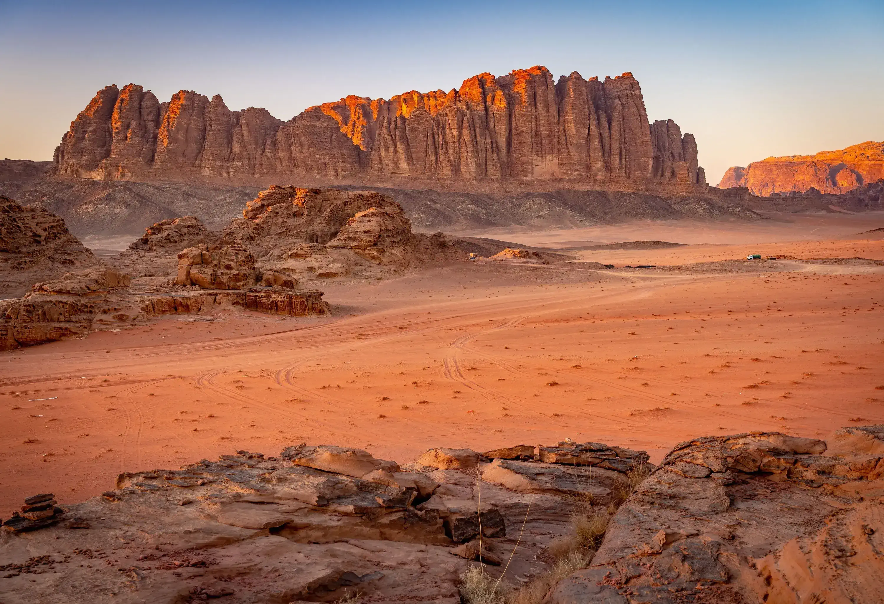 A vast desert with unusual rock formations and distant views of a rugged mountain range.