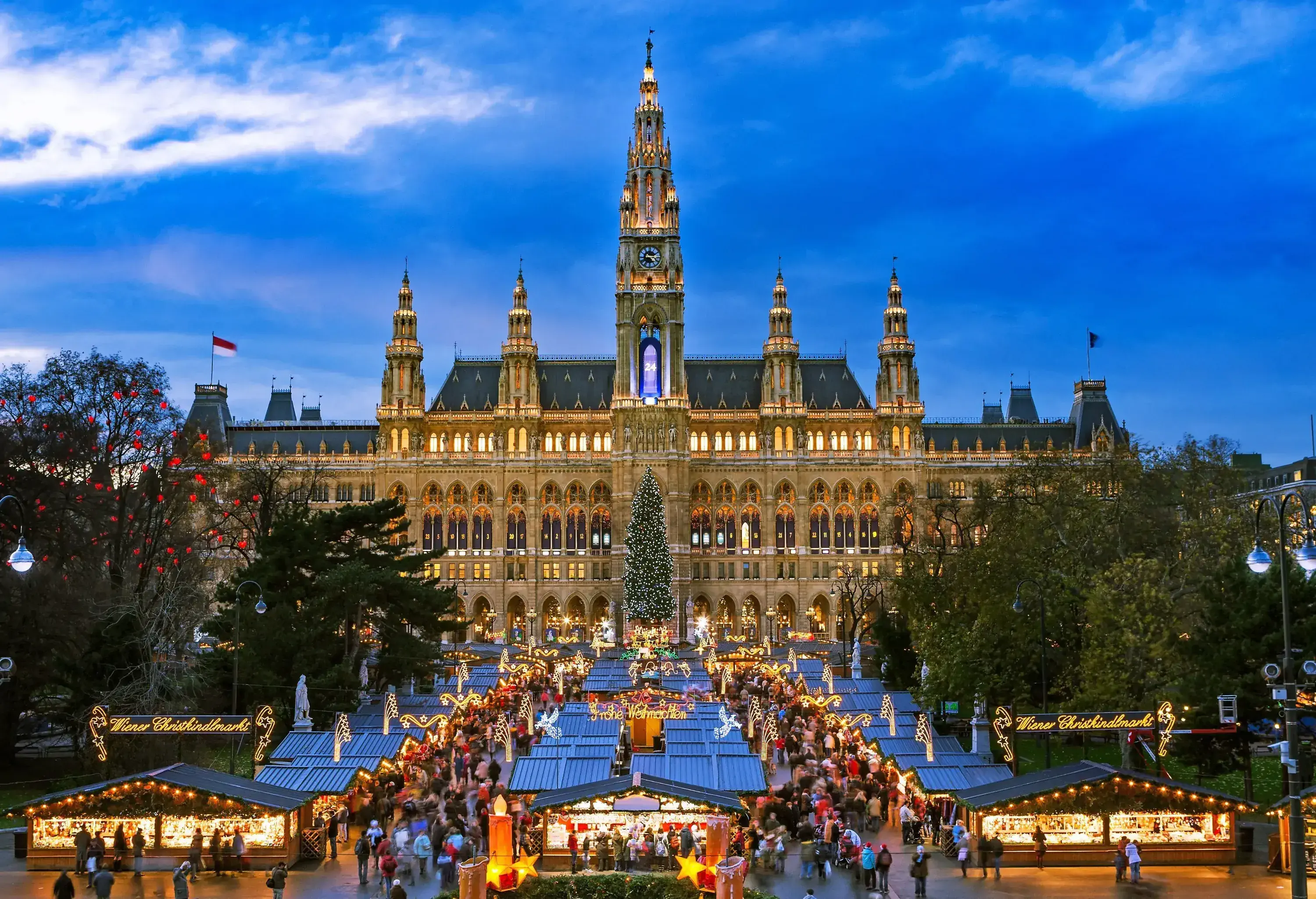 Ornate Christmas market stalls across an impressive Gothic structure with five towers.