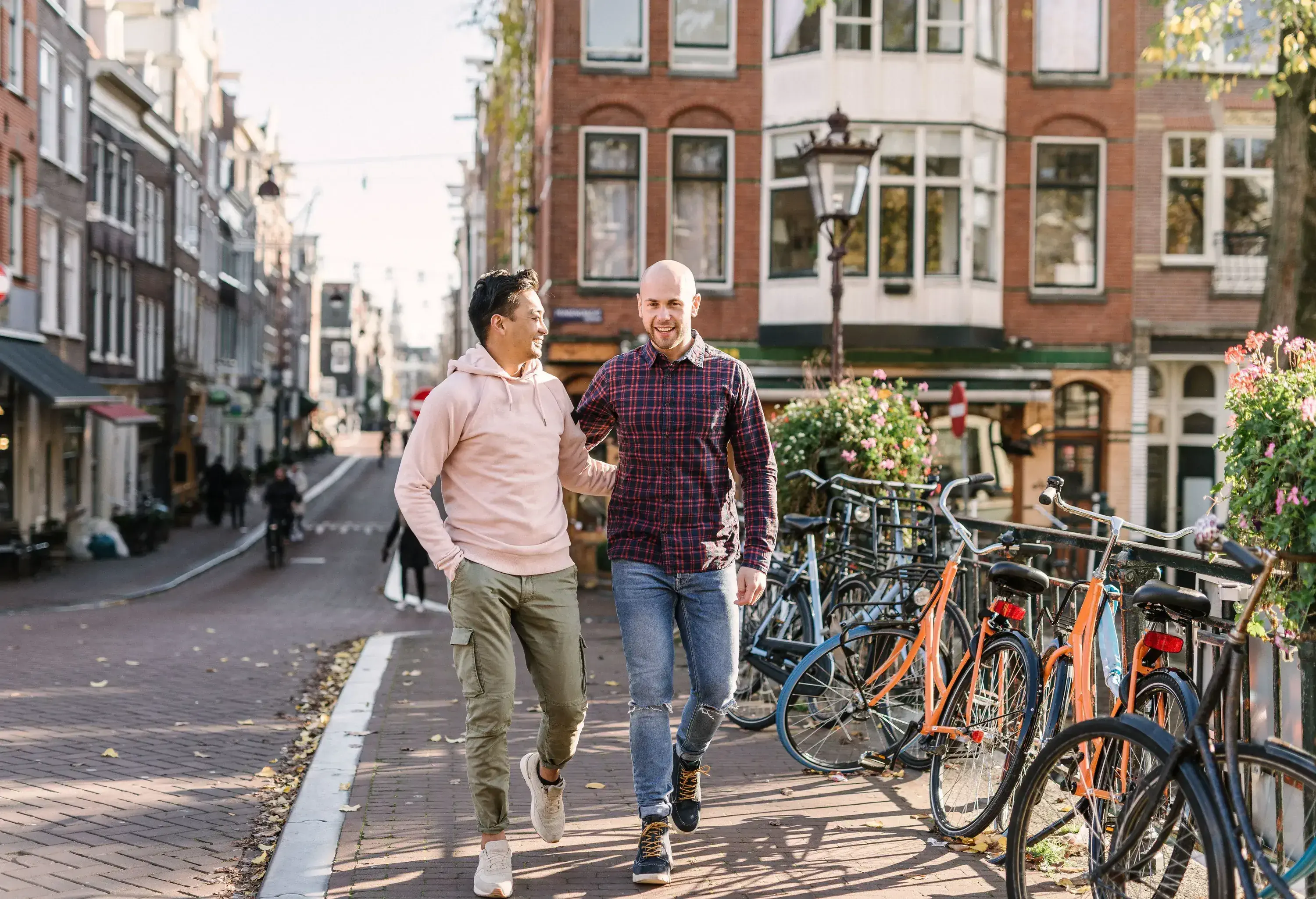 A happy couple walking on a sidewalk with hands on each other's back.