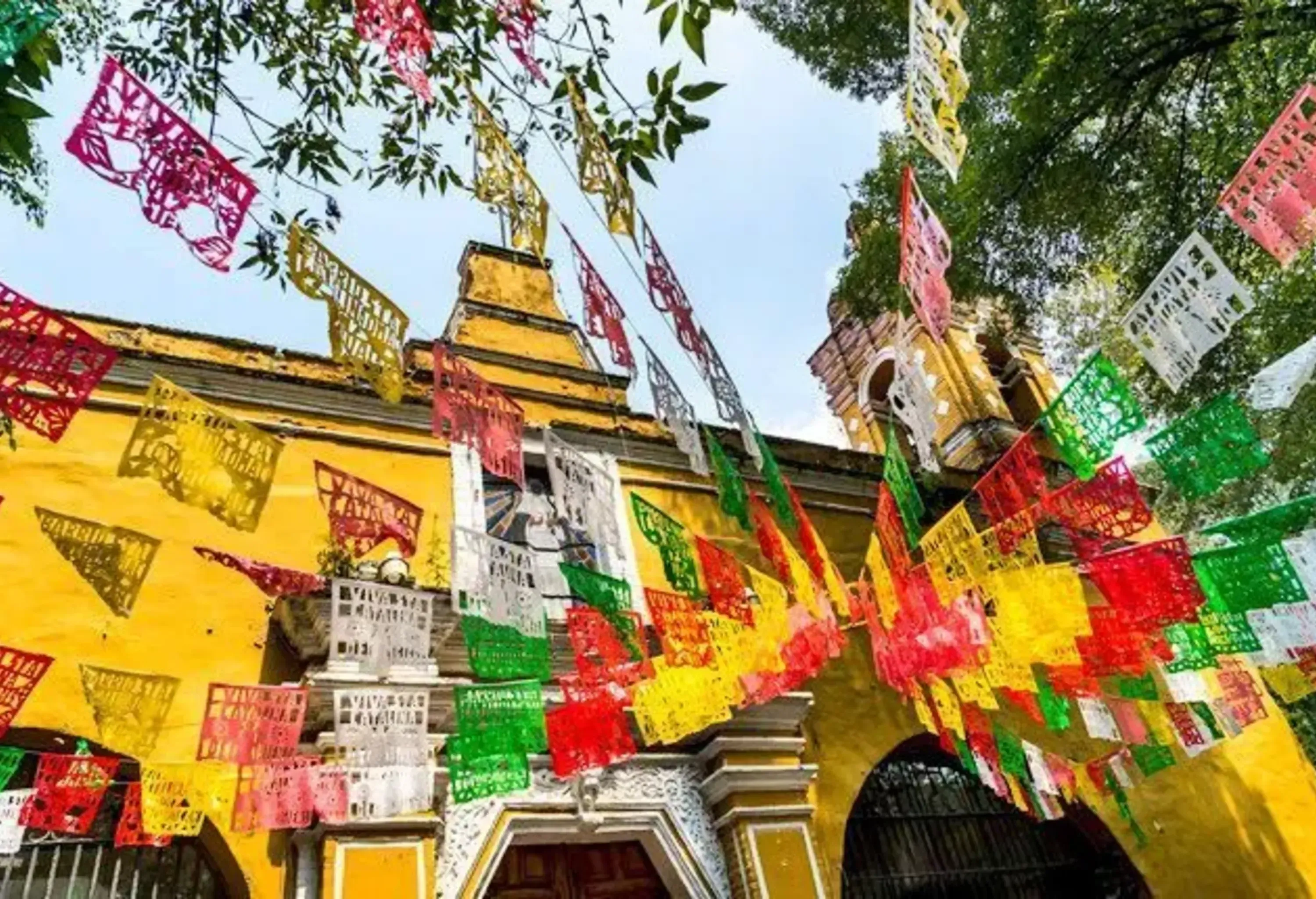 Colourful banners hang in front of a classic yellow building.