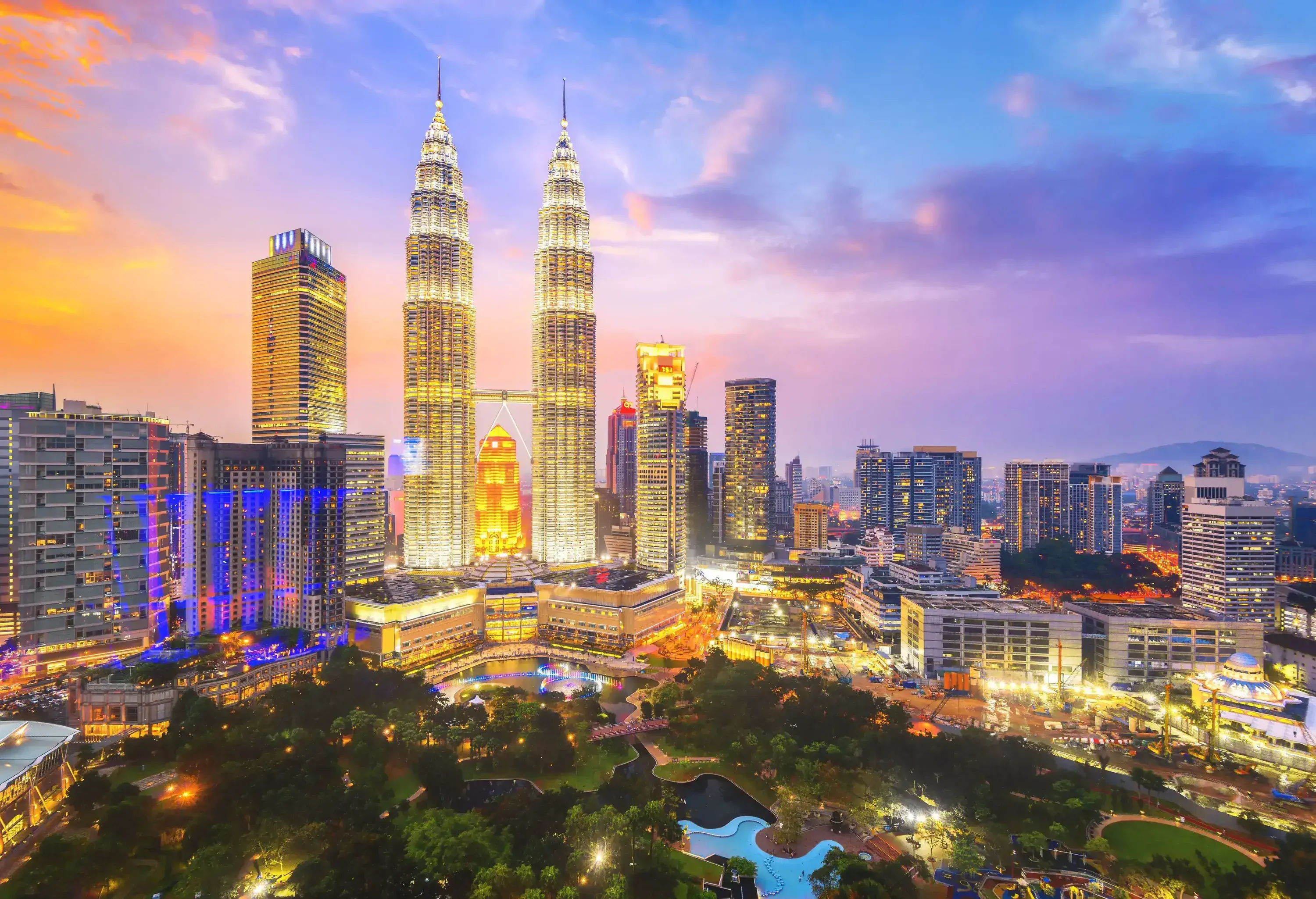 A stunning city skyline lit with bright lights dominated by the beautiful Petronas Twin Towers against the scenic sky.