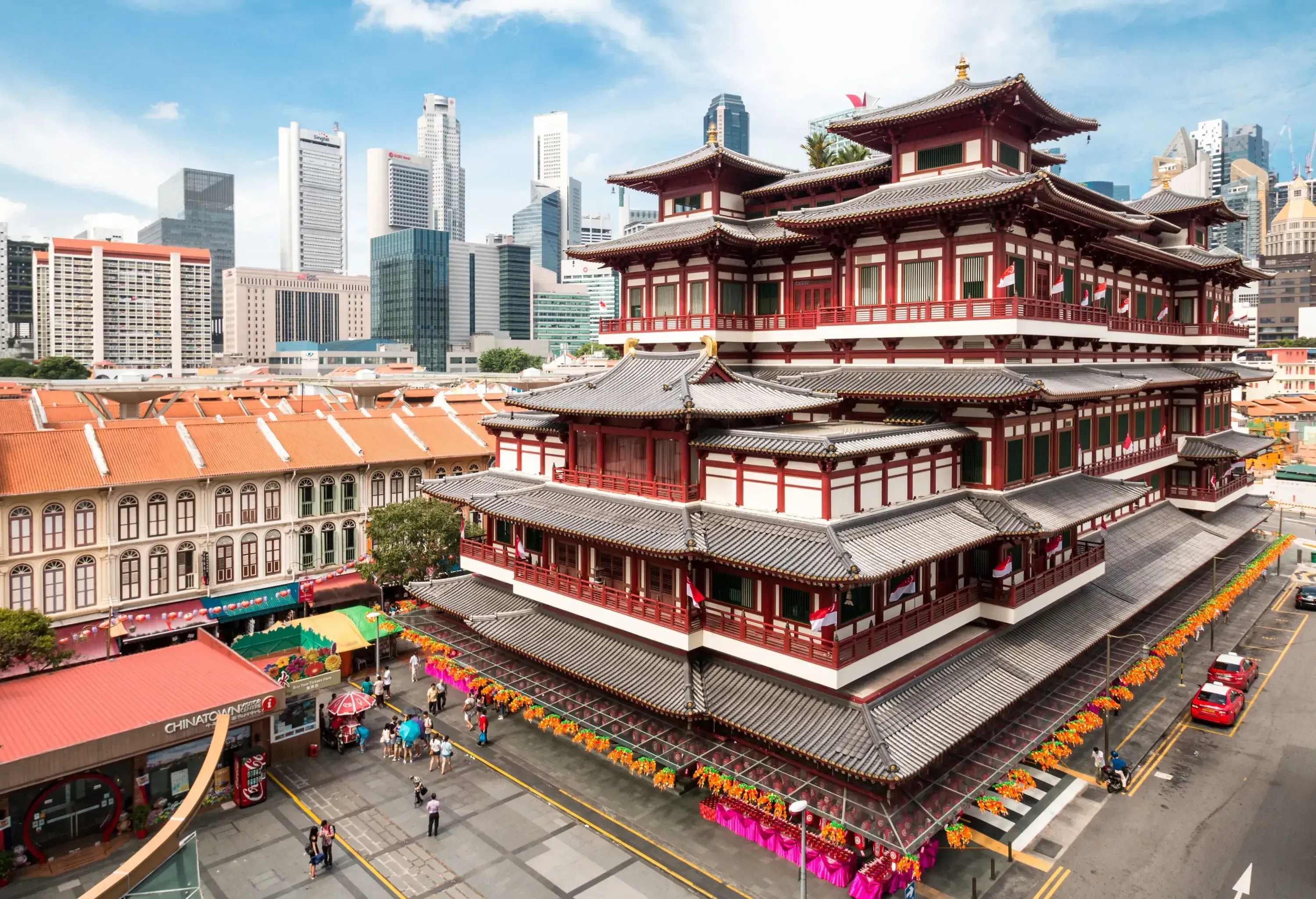 A majestic five-storey Tang-styled Chinese Buddhist temple painted red and white surrounded by tall buildings.