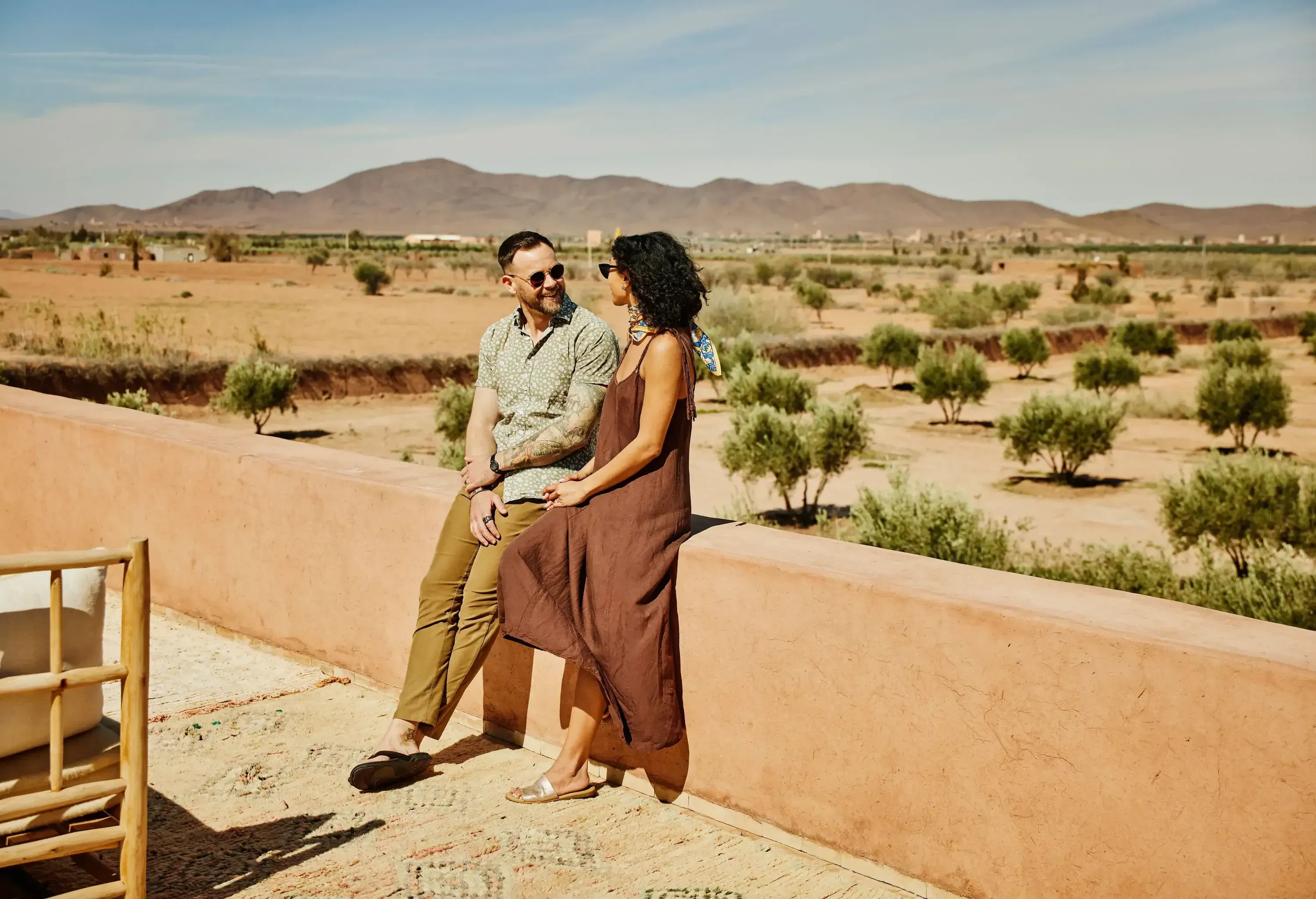 Wide shot of smiling couple relaxing on rooftop terrace of luxury boutique resort during vacation in Morocco