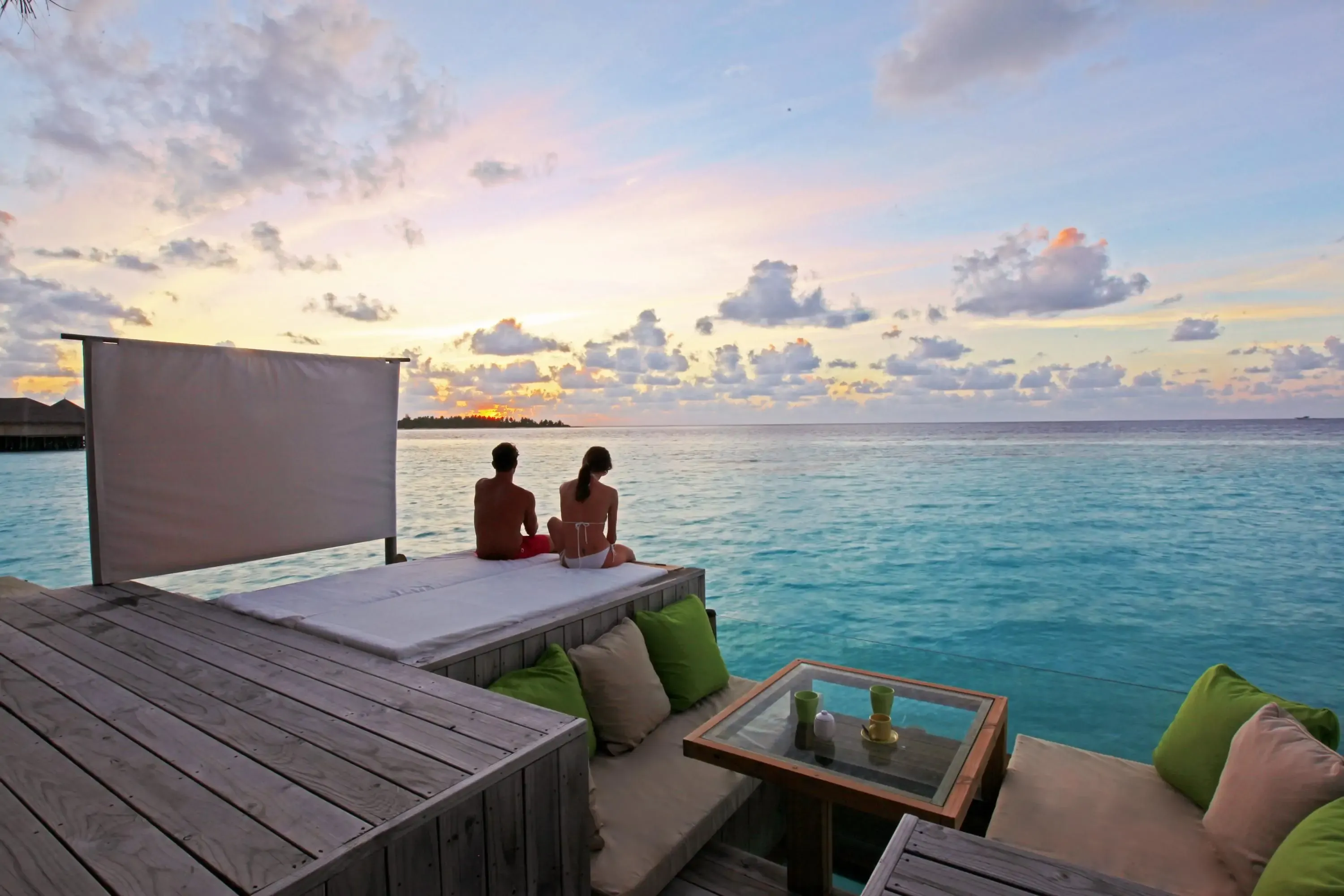 Couple sitting on a deck by the sea water on a tropical island