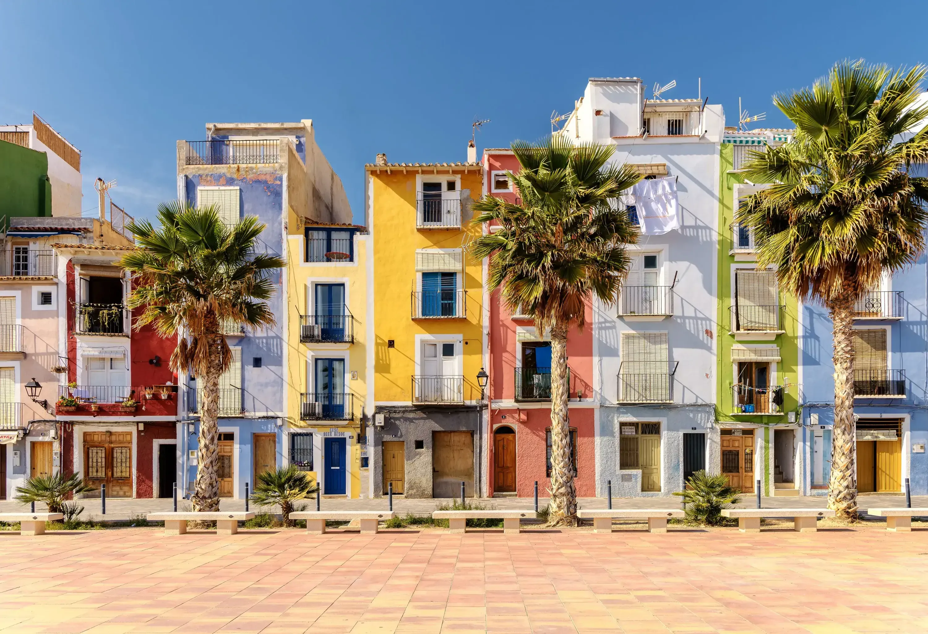 A promenade lined with trees and colourful adjoining buildings.