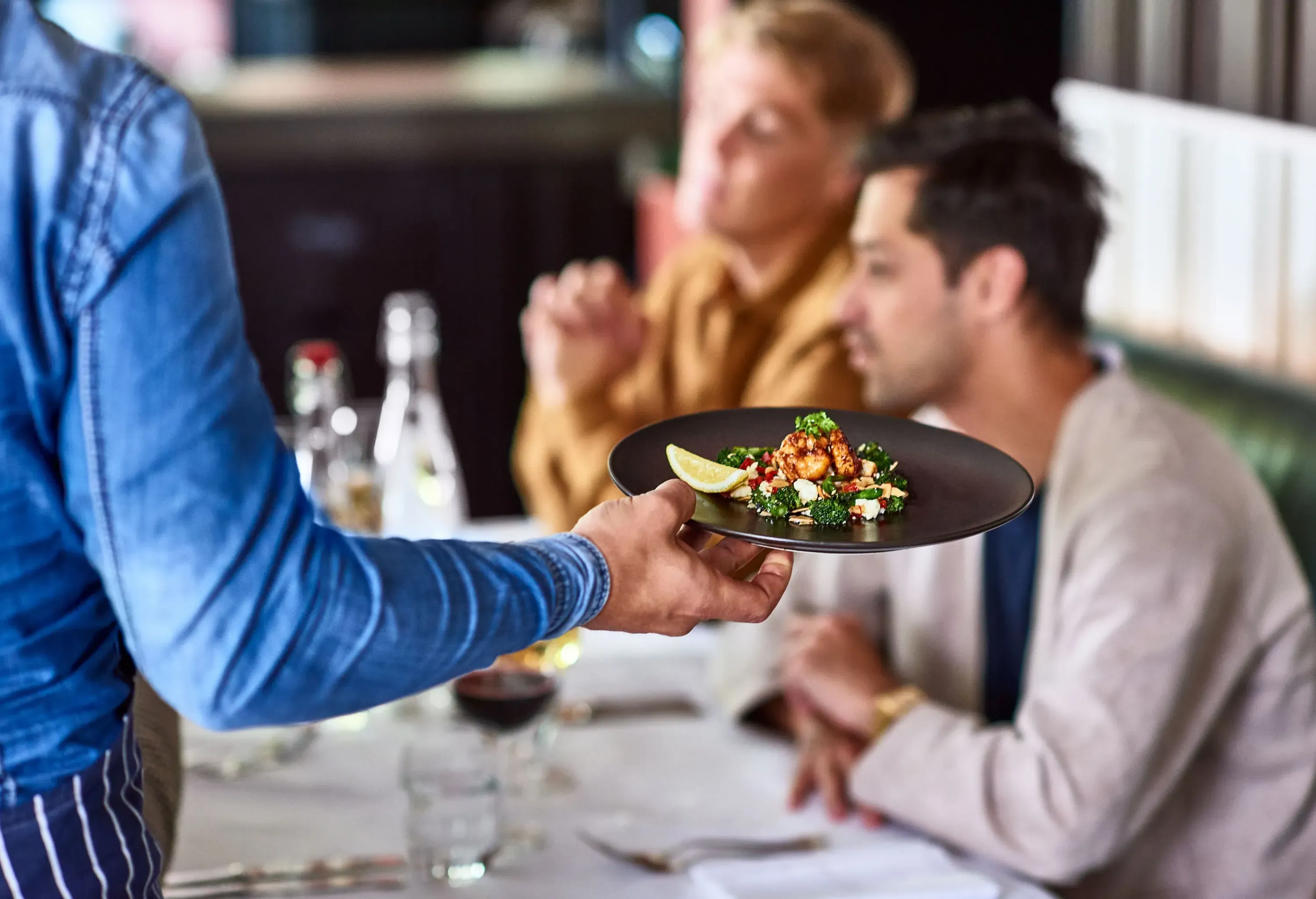 A waiter delivering an order to the customers seated at a table.